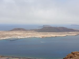 the volcanic island with black soil and a man made harbour in the foreground