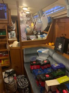 the boat interior with stacks of canned drinks and provisions lying on the bunks and lots of plastic bags hanging up to dry