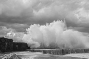 waves crashing over a sea wall