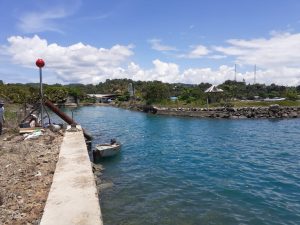 a narrow cut entrance through the land into a boat pond for berthing boats with a concrete wall in the foreground