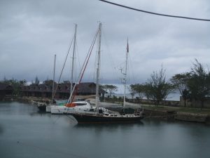 calm pond with yachts in the foreground berthed stern-to the land and small local style huts in the background