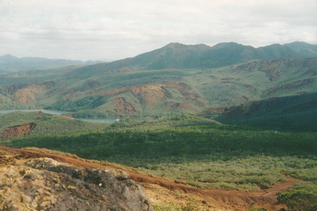 Green mountains and a body of water nestled in the valley with a boat at anchor