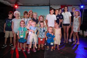 children of all ages standing on the stage with their prizes