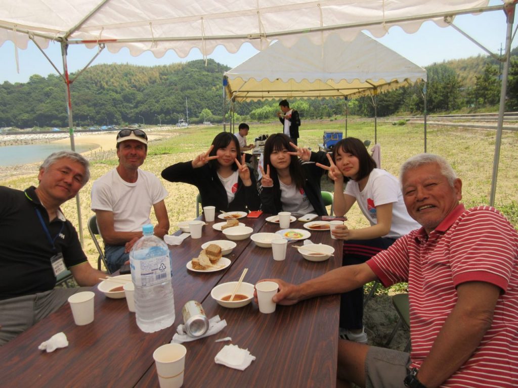 People seated around a table, under a tent.