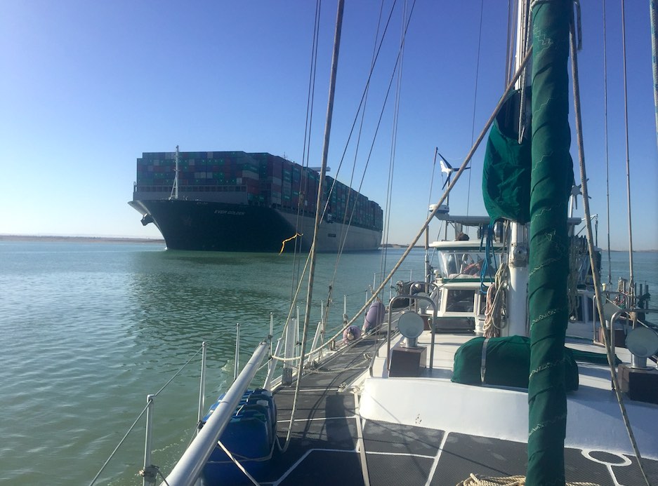 Yacht being passed by a big container ship