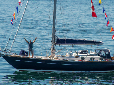 Man standing on bow of yacht and waving.