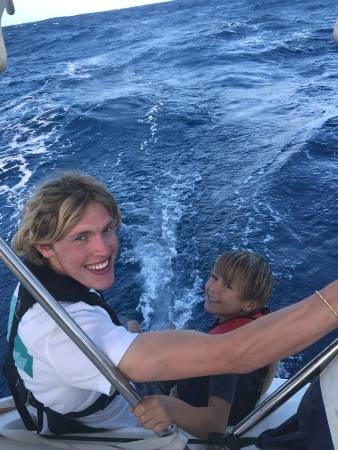 A man and a boy dangling their feet in the water.